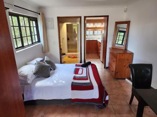 een slaapkamer met een bed, een bureau en een raam bij Cape Cottage in Kaapstad