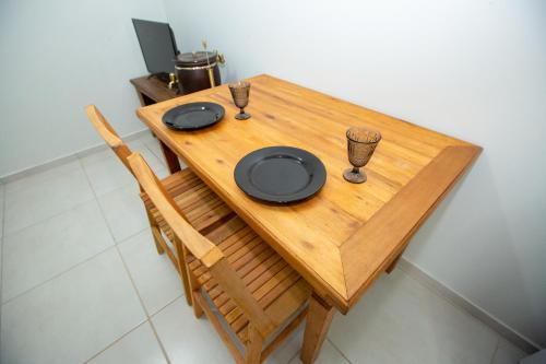 a wooden table with two plates and glasses on it at Jahu Center Village in Jaú