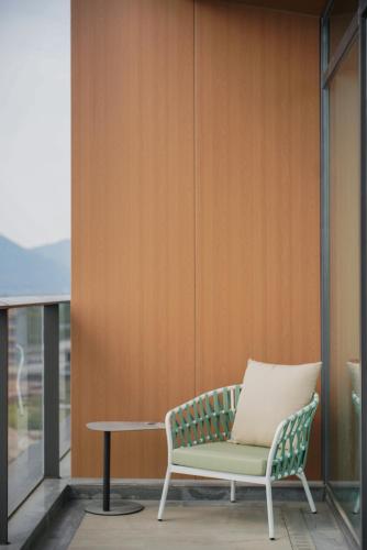 a green chair sitting next to a table with a pillow at New Century Mansion Resort Hangzhou Xianghu Baoyi in Xiaoshan