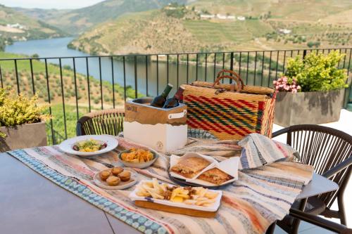 a table with plates of food and a basket of bread at Quinta São Luiz The Vine House Douro in Tabuaço
