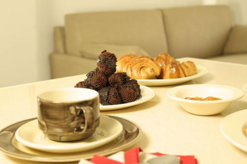 een tafel met borden gebak en een kopje koffie bij Residence San Nicola in Alassio