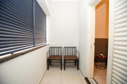 a hallway with two chairs and a window at Jahu Center Village in Jaú