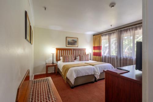 a hotel room with a bed and a television at Knysna Log-Inn Hotel in Knysna