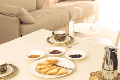 een tafel met een bord brood en kopjes koffie bij Residence San Nicola in Alassio