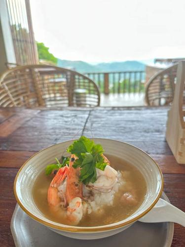 a bowl of soup with shrimp on a table at KHIRI HOUSE &Café Farm ดอยช้างเชียงรายที่พักอาข่าเรียวกังสไตล์กลางหมู่บ้านดอยช้าง in Ban Rong Than