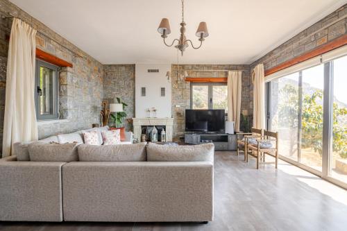 a living room with a couch and a tv at Aurora Spinalonga Garden Cottage in Chavgas