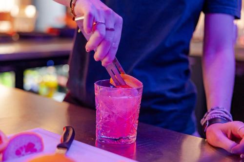 a person is stirring a pink drink on a table at Crowne Plaza Amsterdam - South by IHG in Amsterdam