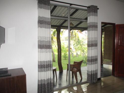 a room with glass doors and a table and a chair at Peacock Lake Villa in Habarana