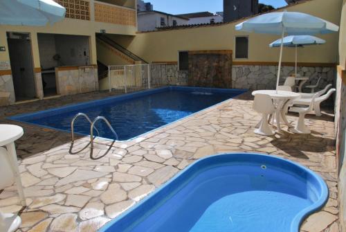 a pool with a table and an umbrella at Hotel Aliança in São Lourenço