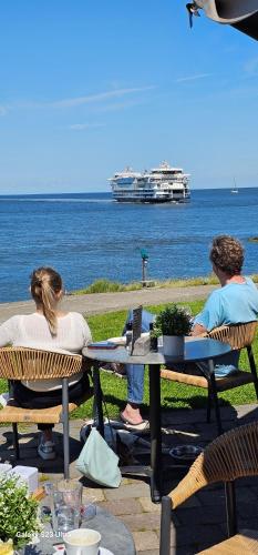 two people sitting at a table looking at the ocean at Romantisch Huisje nabij het strand met uitzicht op de tulpenvelden in Julianadorp