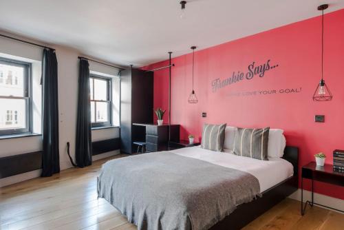 a bedroom with a large bed with a pink wall at Grand Covent Garden 3-bed Penthouse With Terrace in London