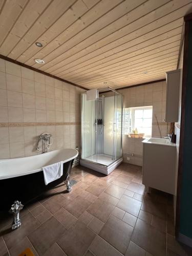 a bathroom with a tub and a shower and a sink at Fryksås Hotell & Gestgifveri in Fryksås
