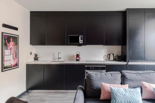 a kitchen with black cabinets and a couch at Vibrant 2-bed Apartment In Soho Near Theatreland in London