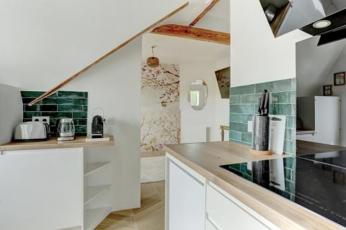 une cuisine avec des placards blancs et du carrelage vert dans l'établissement Le Gresset - Vanves, à Vanves