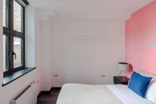 a bedroom with a white bed and a pink wall at Striking 2-bed Apartment Perfectly Located in Soho in London