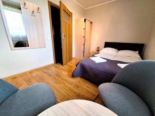 a bedroom with a bed and two chairs in it at Pokoje Gościnne Maczek in Sztutowo