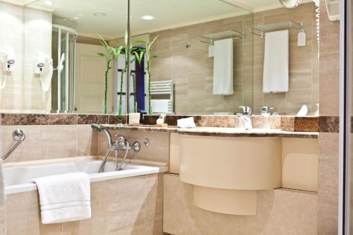 a bathroom with a tub and a sink at Hotel Le Châtelain in Brussels