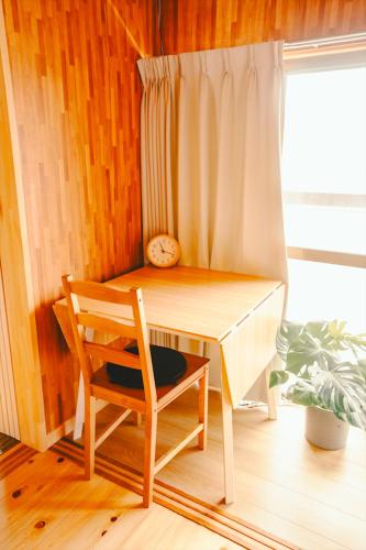 a desk with a chair and a clock next to a window at NorthStar Sea Breeze Holiday Home in Shimoda