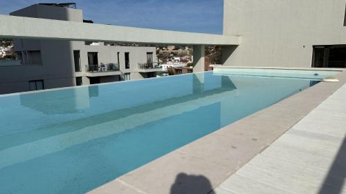 a blue swimming pool in front of a building at Sundara Tan perfecto que no vas a querer irte in Villa Carlos Paz