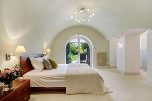 - une chambre avec un grand lit et une fenêtre cintrée dans l'établissement Mas de La Tour, à Saint-Tropez