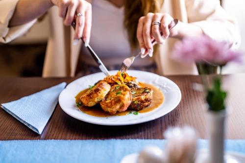 a woman sitting at a table with a plate of food at Hotel Gong in Štramberk