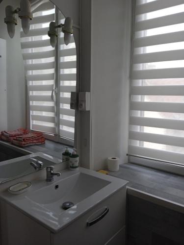 a bathroom with a white sink and a mirror at Chambres d'hôtes les Clématites en Cotentin in Saint-Floxel