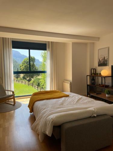 ein Schlafzimmer mit einem großen Bett und einem großen Fenster in der Unterkunft Ventanal de Saras Petfriendly Garaje Trastero y Chimenea - Arafita Apartamentos in Panticosa