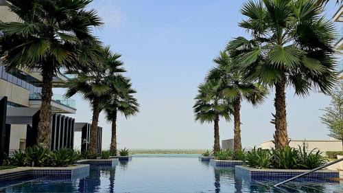a swimming pool with palm trees in front of a building at Voyage 2 Bedroom In Mayan With Ocean Views in Abu Dhabi
