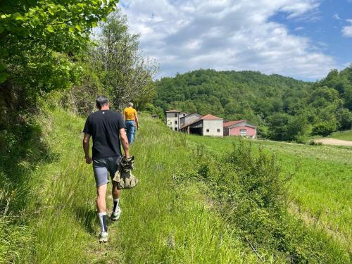 two men walking down a grassy path with a dog at Casavabene in Murazzano