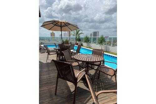 a patio with tables and chairs and an umbrella at Studio Sublime West Flat Mossoró in Mossoró
