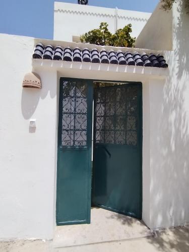 a white house with a green door and window at Appartement T2 60m2 Djerba Houmet Essouk in Houmt Souk