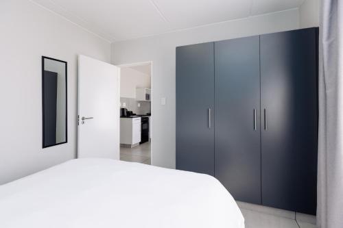 a white bedroom with a bed and blue cabinets at MINT Express Sandton View in Johannesburg