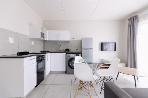 a kitchen with white appliances and a table and chairs at MINT Express Sandton View in Johannesburg