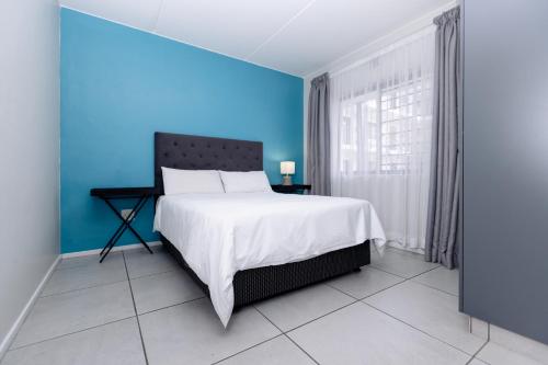 a blue bedroom with a bed and a blue wall at MINT Express Sandton View in Johannesburg