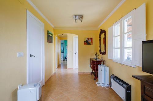 a hallway with yellow walls and a tv and a window at Casa Vieje de Bueu in Bueu