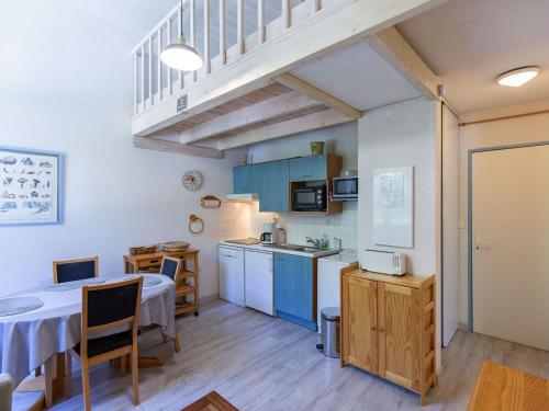 une cuisine avec des armoires bleues et une table avec une table dans l'établissement Appartement cosy 5 pers avec mezzanine et équipements à Barèges - FR-1-403-49, à Barèges
