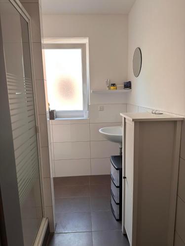 a white bathroom with a sink and a window at AM Apartment in Gronau
