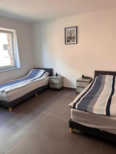 two beds sitting in a room with a tile floor at AM Apartment in Gronau