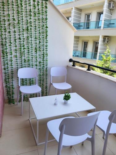 Un patio con sillas blancas y una mesa en un balcón. en Aron Home, en Tushemisht
