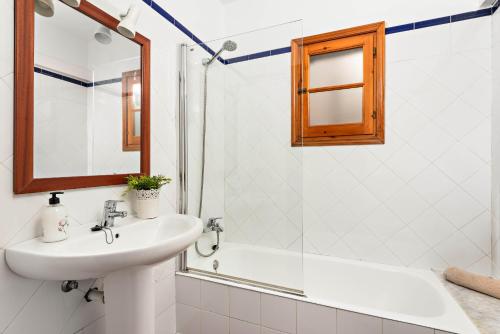 a bathroom with a sink and a mirror and a tub at Villas Playas de Fornells in Fornells