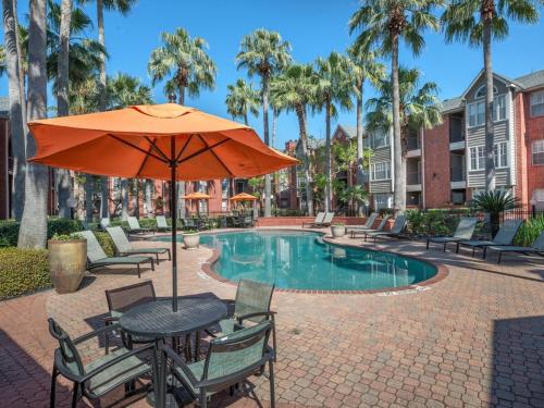 a table with an umbrella and chairs next to a pool at Med Center Charm 2br Haven in Houston