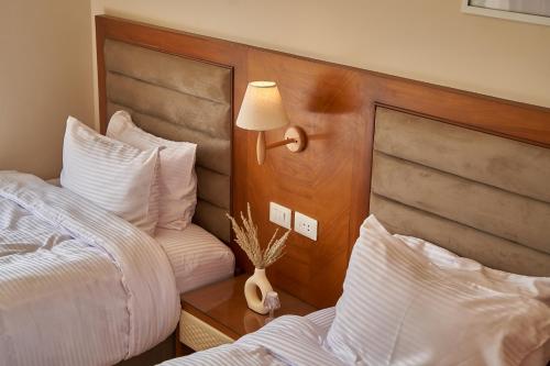 a bedroom with two beds and a lamp on the wall at prestige pyramids INN in Cairo