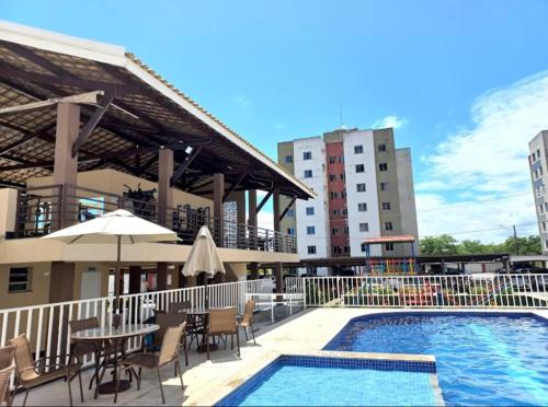 a swimming pool with tables and chairs next to a building at Bela Providência in Aracaju