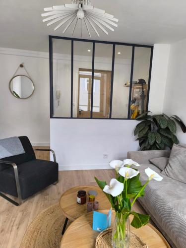 un salon avec un canapé et une table avec des fleurs dans l'établissement Appartement spacieux et moderne, en plein centre, à Boulogne-sur-Mer