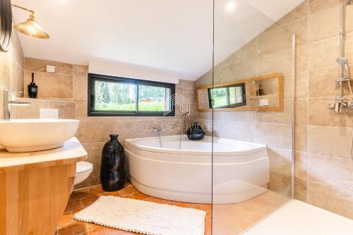 une salle de bain avec une baignoire et un lavabo dans l'établissement Domaine de Syrka à Deauville, à Saint-Étienne-la-Thillaye