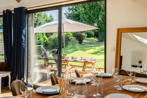 - une salle à manger avec une table et un parasol dans l'établissement Domaine de Syrka à Deauville, à Saint-Étienne-la-Thillaye