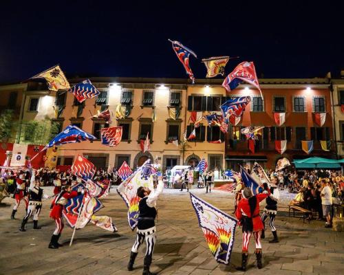 a group of people flying kites in front of a building at Rovaio in Fivizzano