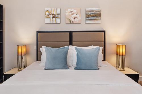 a bedroom with a bed with blue pillows and two lamps at La Buena Vida Holiday Homes - Modern, Luxe & Spacious 4-Bed, Full Kitchen, near to Beach, Tram & Marina in Dubai