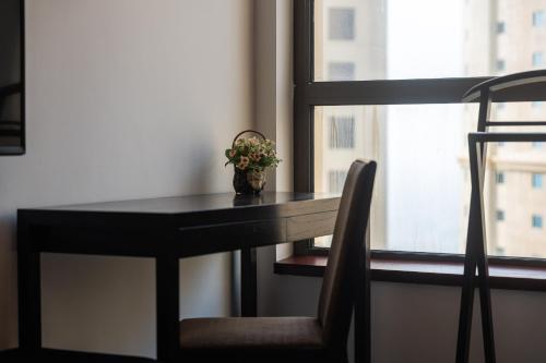 a table and a chair with a vase of flowers at La Buena Vida Holiday Homes - Modern, Luxe & Spacious 4-Bed, Full Kitchen, near to Beach, Tram & Marina in Dubai
