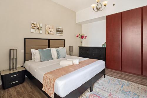 a bedroom with a large bed and a cabinet at La Buena Vida Holiday Homes - Modern, Luxe & Spacious 4-Bed, Full Kitchen, near to Beach, Tram & Marina in Dubai